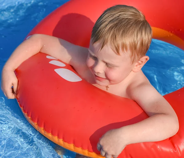 Kleine jongen op een opblaasbare cirkel in het water — Stockfoto