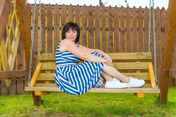 Brunette vrouw op een houten bankje — Stockfoto