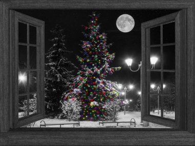 Gece açık bir pencereden bir manzara çelenkli bir Noel ağacı
