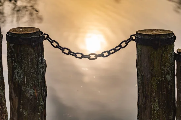 湖に鉄の鎖と柱がある古い木製の桟橋 — ストック写真