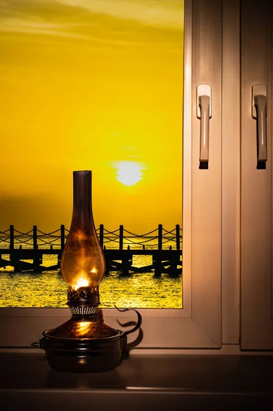 窓からの日没時の窓辺の古いオイルランプ — ストック写真