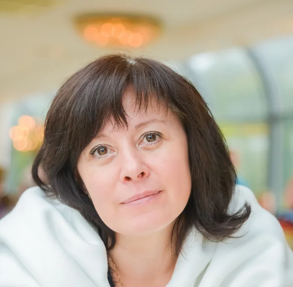 Middle-aged woman brown eyes is sitting in the apartment — Stock Photo, Image