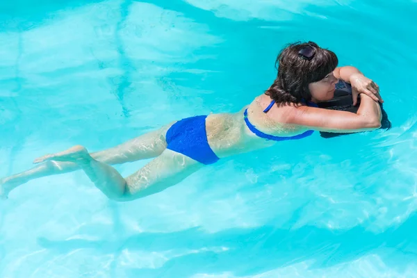 Mulher está deitada perto da piscina — Fotografia de Stock