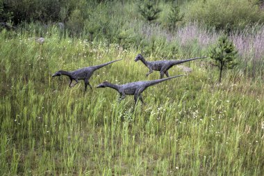 Dinozorlar Parkı. Doğanın arka planında bir dinozor. Lunaparktaki oyuncak dinozorlar..