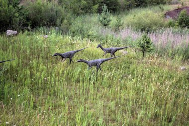 Dinozorlar Parkı. Doğanın arka planında bir dinozor. Lunaparktaki oyuncak dinozorlar..