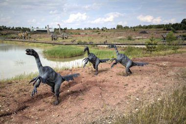 Dinozorlar Parkı. Doğanın arka planında bir dinozor. Lunaparktaki oyuncak dinozorlar..