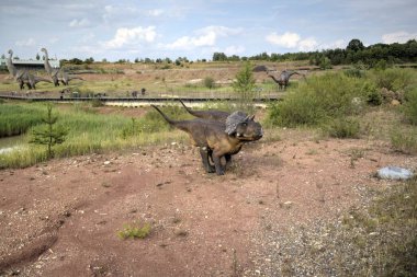 Dinozorlar Parkı. Doğanın arka planında bir dinozor. Lunaparktaki oyuncak dinozorlar..