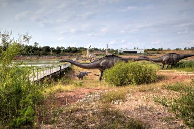 Dinozorlar Parkı. Doğanın arka planında bir dinozor. Lunaparktaki oyuncak dinozorlar..