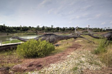 Dinozorlar Parkı. Doğanın arka planında bir dinozor. Lunaparktaki oyuncak dinozorlar..
