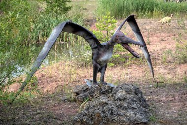 Dinozorlar Parkı. Doğanın arka planında bir dinozor. Lunaparktaki oyuncak dinozorlar..