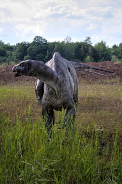 Dinozorlar Parkı. Doğanın arka planında bir dinozor. Lunaparktaki oyuncak dinozorlar..