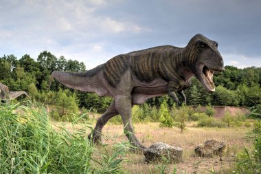 Dinozorlar Parkı. Doğanın arka planında bir dinozor. Lunaparktaki oyuncak dinozorlar..