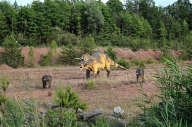 Dinozorlar Parkı. Doğanın arka planında bir dinozor. Lunaparktaki oyuncak dinozorlar..