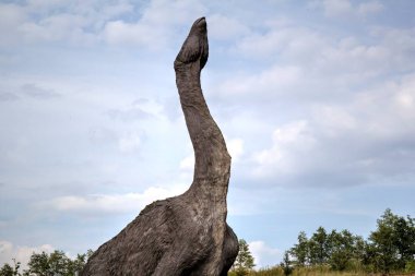Dinozorlar Parkı. Doğanın arka planında bir dinozor. Lunaparktaki oyuncak dinozorlar..