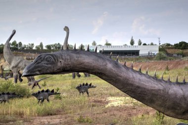 Dinozorlar Parkı. Doğanın arka planında bir dinozor. Lunaparktaki oyuncak dinozorlar..