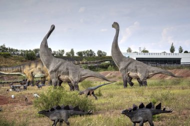 Dinozorlar Parkı. Doğanın arka planında bir dinozor. Lunaparktaki oyuncak dinozorlar..