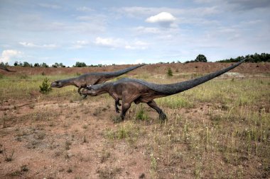 Dinozorlar Parkı. Doğanın arka planında bir dinozor. Lunaparktaki oyuncak dinozorlar..