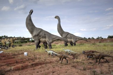Dinozorlar Parkı. Doğanın arka planında bir dinozor. Lunaparktaki oyuncak dinozorlar..