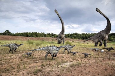Dinozorlar Parkı. Doğanın arka planında bir dinozor. Lunaparktaki oyuncak dinozorlar..