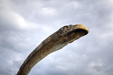 Dinozorlar Parkı. Doğanın arka planında bir dinozor. Lunaparktaki oyuncak dinozorlar..