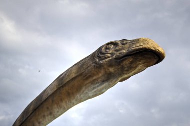 Dinozorlar Parkı. Doğanın arka planında bir dinozor. Lunaparktaki oyuncak dinozorlar..