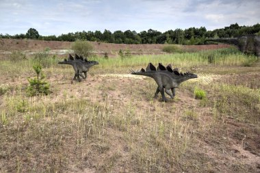 Dinozorlar Parkı. Doğanın arka planında bir dinozor. Lunaparktaki oyuncak dinozorlar..