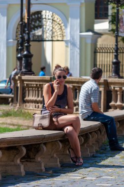 Timisoara, Romanya - 02 Eylül 2013: Sokakta bir bankta dinlenen ve telefonuyla konuşan kadın. Gerçek insanlar..
