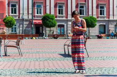 Timisoara, Romanya - 27 Haziran 2017: Sokakta yürüyen ve telefonunu kontrol eden kadın. Gerçek insanlar..