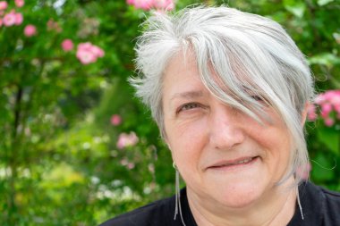 Timisoara, Romanya - 30 Mayıs 2020: Arkasında güller olan bir kadın portresi. Gri saç.