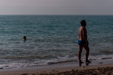 Sahilde yürüyen insanların silueti. Tanınmayan insanlar. Denize odaklan.