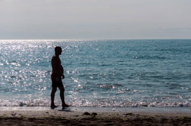 Sahilde yürüyen insanların silueti. Tanınmayan insanlar. Denize odaklan.
