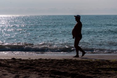 Sahilde yürüyen insanların silueti. Tanınmayan insanlar. Denize odaklan.
