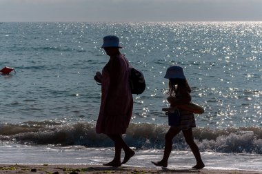 Sahilde yürüyen insanların silueti. Tanınmayan insanlar. Denize odaklan.