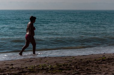 Sahilde yürüyen insanların silueti. Tanınmayan insanlar. Denize odaklan.