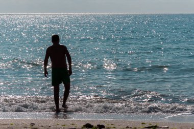 Sahilde yürüyen insanların silueti. Tanınmayan insanlar. Denize odaklan.