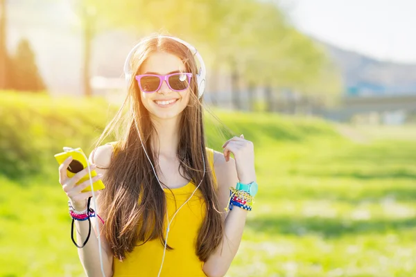 Menina adolescente alegre fresco com telefone inteligente e fones de ouvido Imagens De Bancos De Imagens