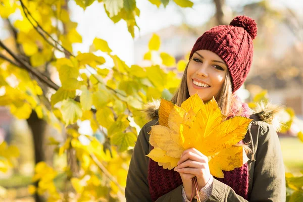 Счастливая молодая женщина осенью в парке держит листья — стоковое фото