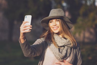 Modern genç kadın bir selfie Park'ta sonbaharda alarak.