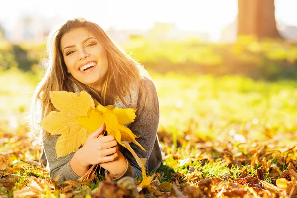 Hermosa joven feliz en parque sosteniendo hojas — Foto de Stock