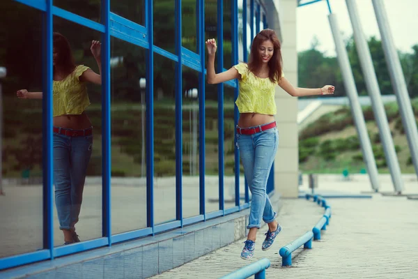 Sonriente chica hipster divertido en pantalones vaqueros azules corriendo y saltando — Foto de Stock