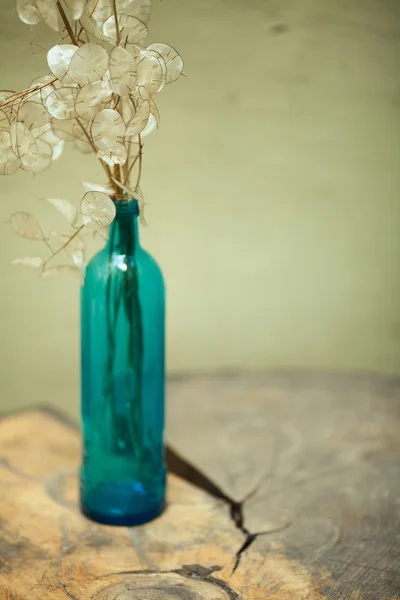 Arty, creative composition of dry branches with leaves in blue glass bottle — Stock Photo, Image