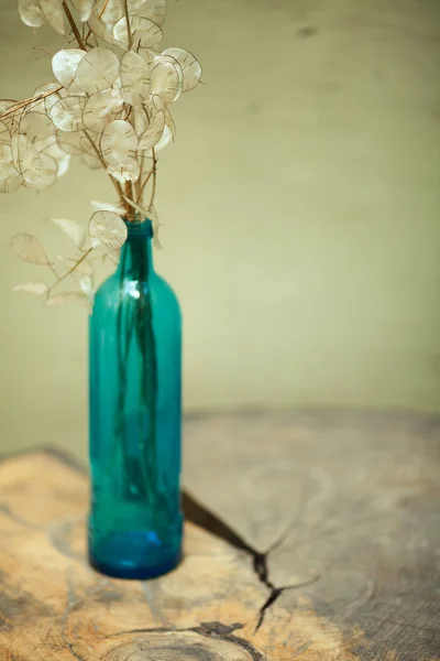 Arty, creative composition of dry branches with leaves in blue glass bottle Stock Image