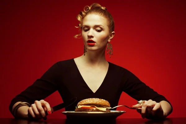 Fashion & Gluttony Concept. Retrato de lujoso modelo de pelo rojo con hamburguesa —  Fotos de Stock