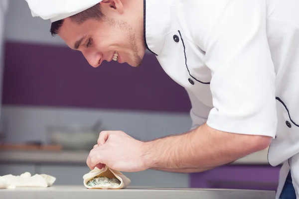 Vegetarian bakery concept. Smiling cook putting filler of spinach — Stock Photo, Image