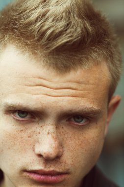 Kameraya bakarak yüzündeki güneş lekeleri ile yakışıklı genç