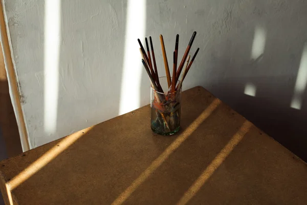 Equipo para concepto de pintura. Un vaso con pinceles sobre cubo de madera — Foto de Stock