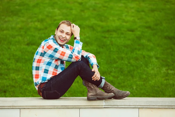 Portrét šťastný šťastný mladík relaxační poblíž zelený trávník v parku — Stock fotografie