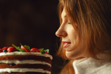 Doğum gününde güzel bir bayana nefis bir hediye. Beyaz, parlak bir gülümseme. Profil portresini çikolatalı pastayla kapat. Kopyalama uzayı. Kapalı çekim