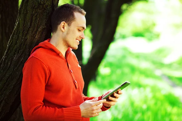 Gadget user concept. Portrait of happy young guy in orange sweat — Stock Photo, Image