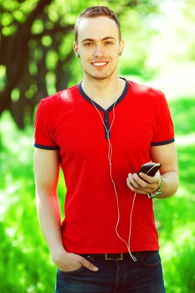 빨간 t-셔츠에 음악을 듣고 있는 행복 한 젊은이의 초상 — 스톡 사진